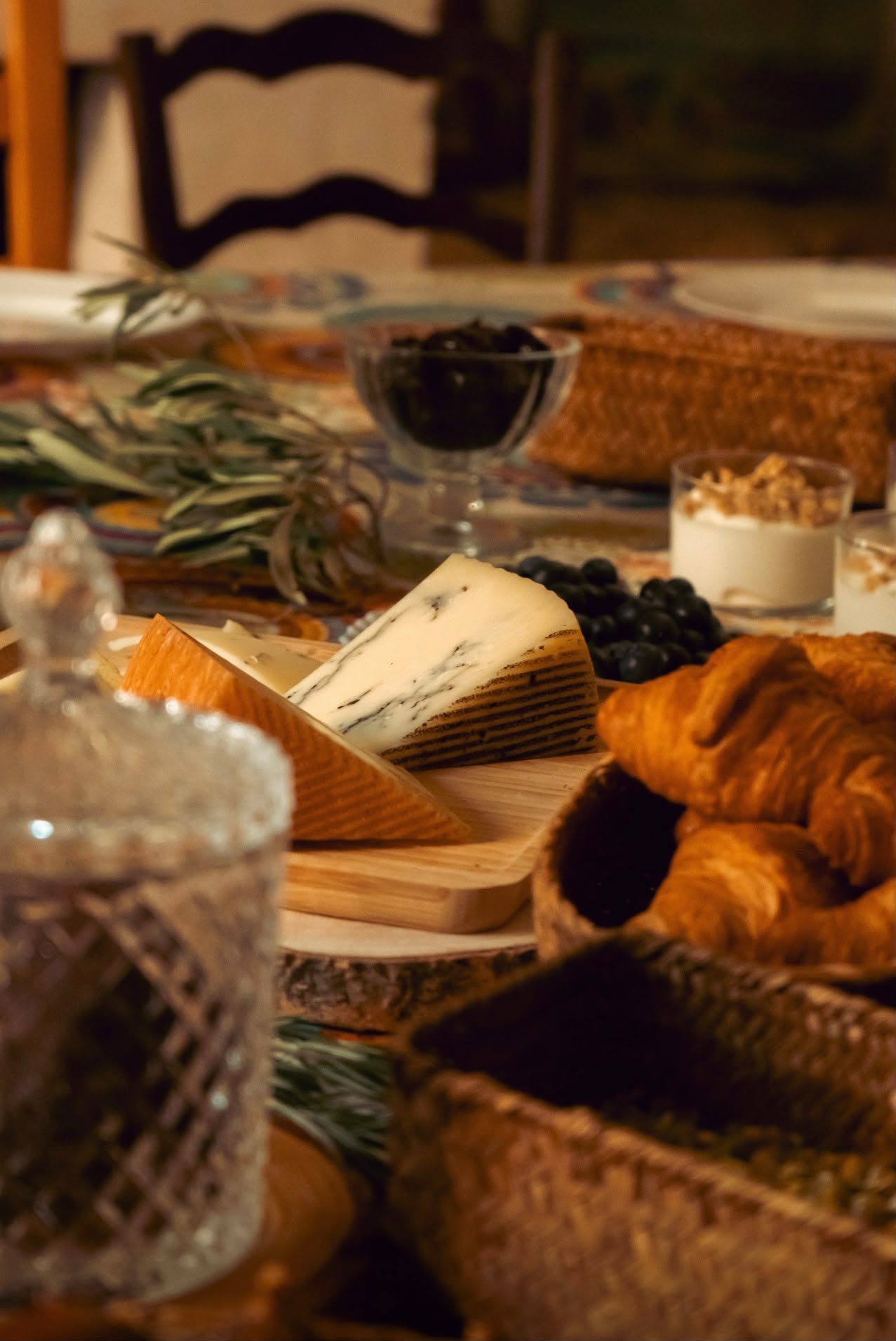 A board of cheeses, croissants and olives on the table