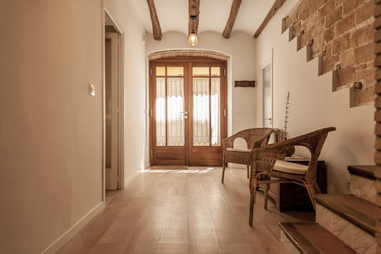 Beamed hallway with wicker chairs and a tall wooden double door