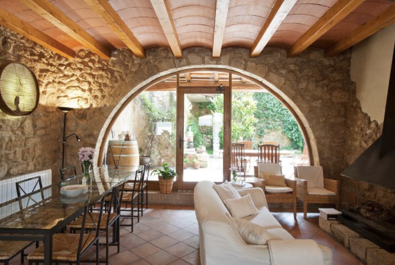 Living room with an original stone arch, wooden beams and doors opening to the garden
