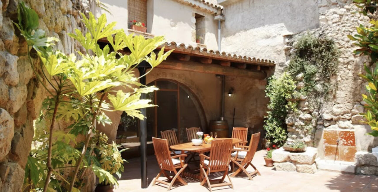 Shaded stone terrace with a long wooden dining table under a tiled arch