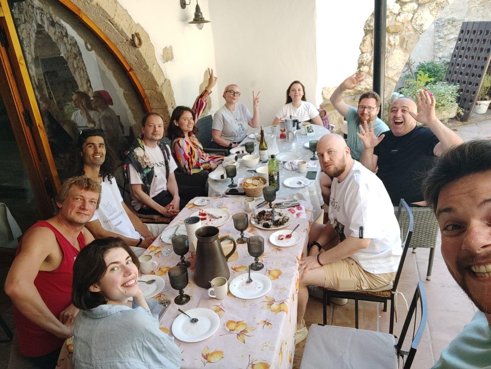 The whole group at the long table under the stone arches, glasses raised