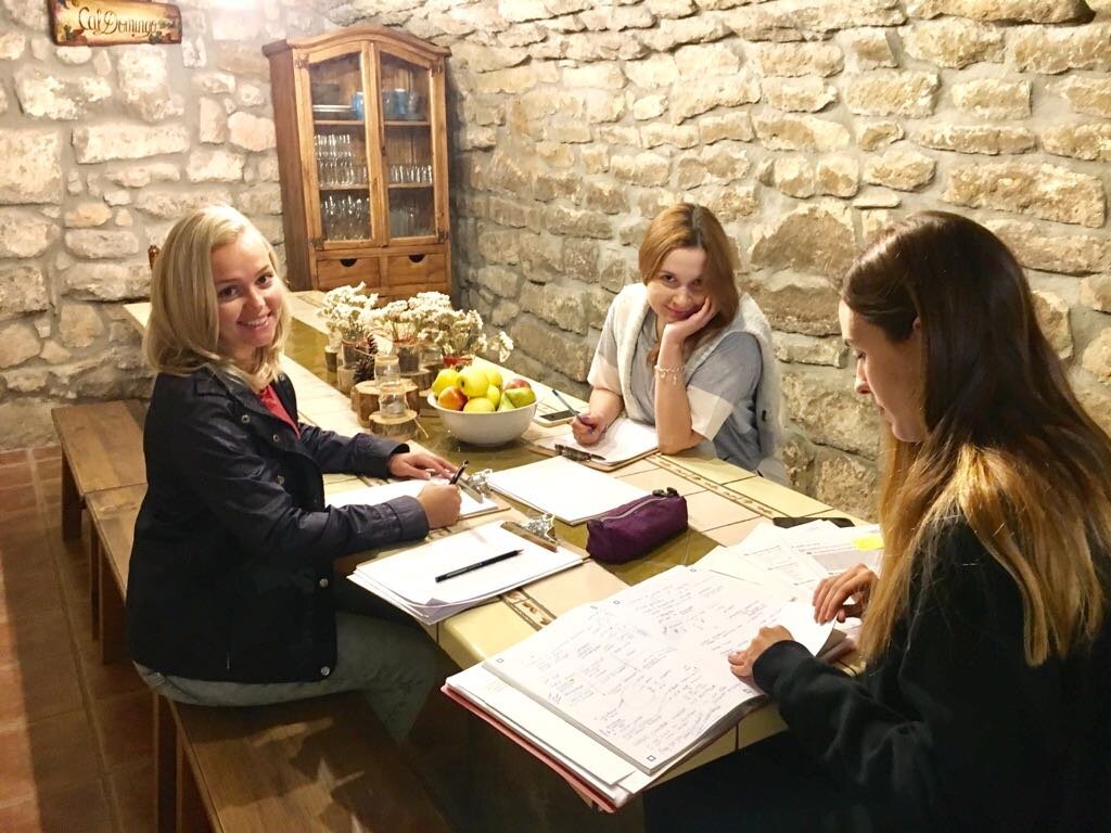 Three guests working through a Spanish exercise beside the old stone wall
