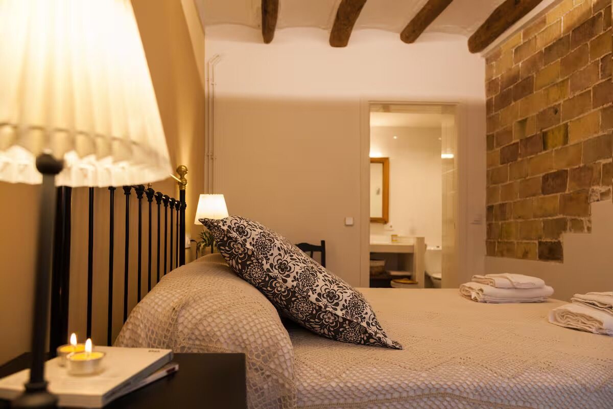 A double bedroom with an exposed brick wall and a wooden headboard