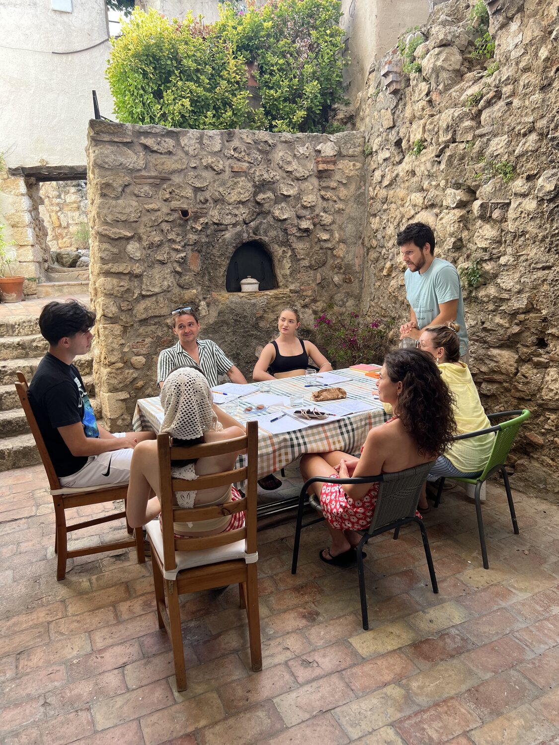 Guests around the table in the stone courtyard on a sunny afternoon