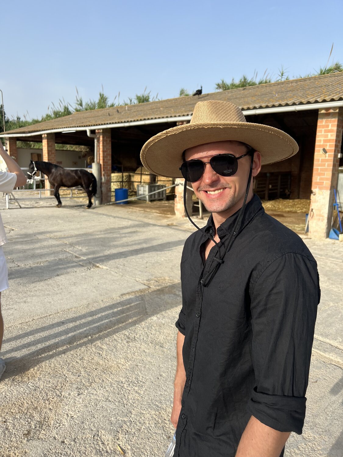 A guest in an Escapada Lingüística straw hat at the stables before the ride