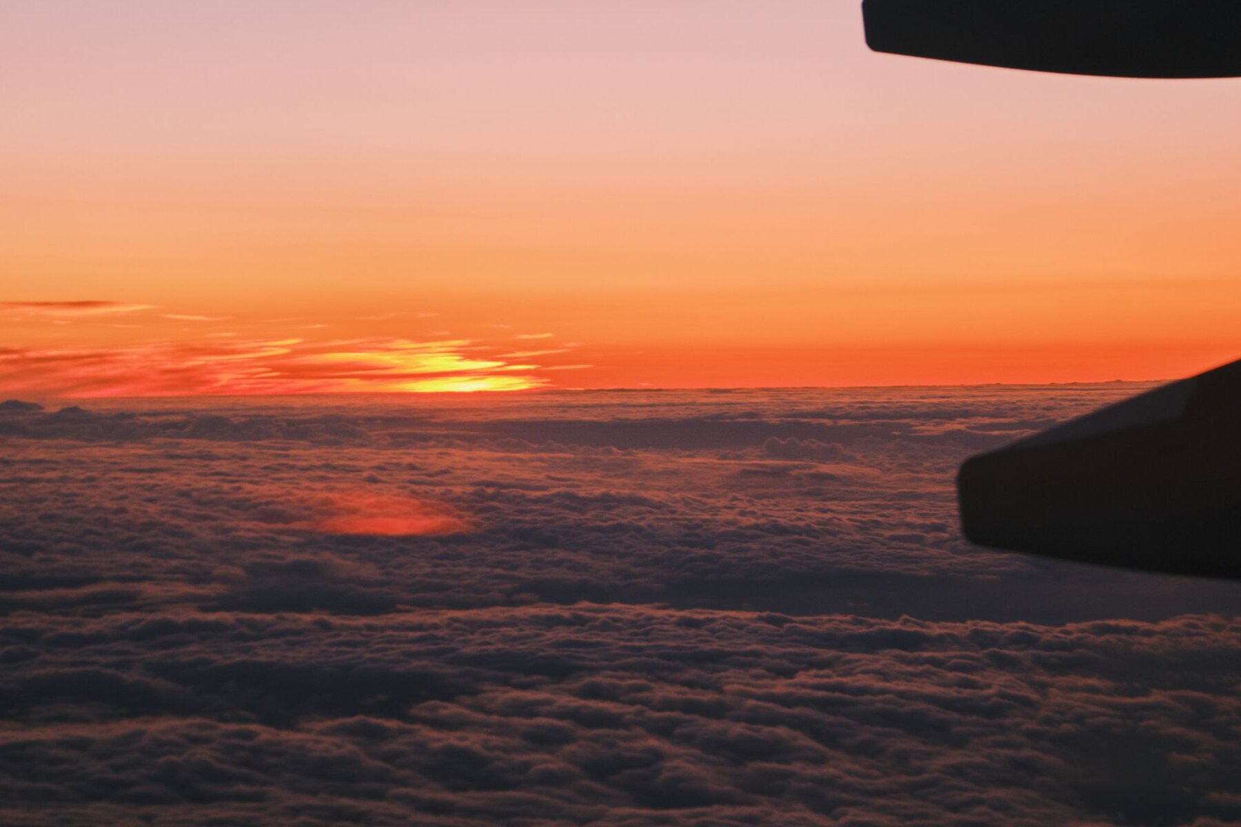 View of a warm sunset over the clouds from an aircraft wing